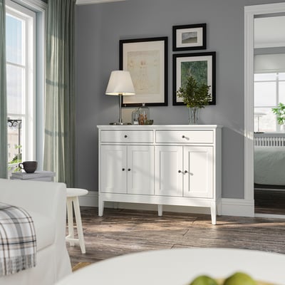 White IDANÄS sideboard with bifold doors and drawers against dark gray walls, styled with decor and lamps.