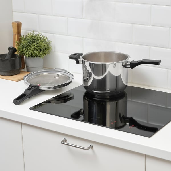 Modern kitchen with ikea pressure cooker on induction hob, pan, and wooden utensils.