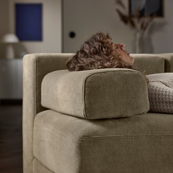 A person relaxes on a comfortable JÄTTEBO sofa, leaning against soft cushions designed for support and comfort.