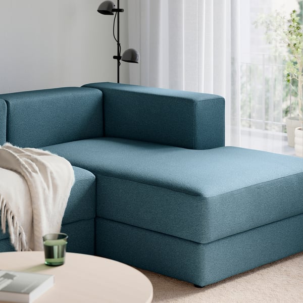 Blue modular sofa with a chaise longue, soft cushions, and a cup on a nearby table.