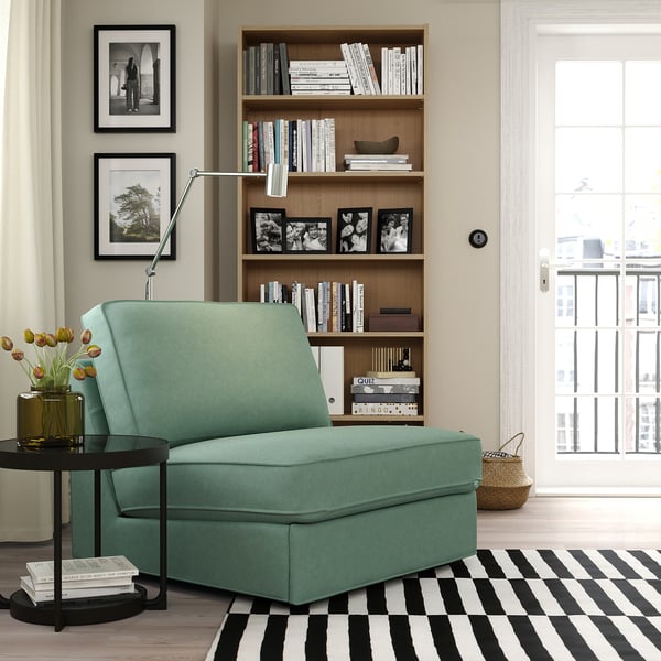 Cosy green KIVIK sofa-bed, compact for small spaces, by large bookcase and window.