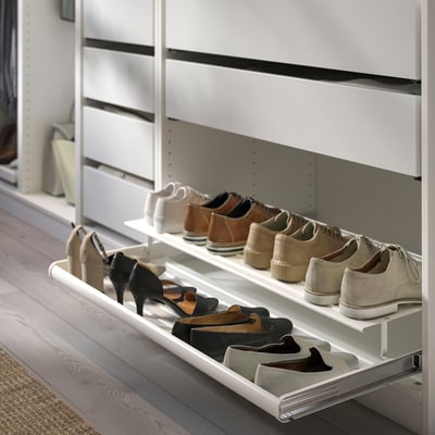 Organised white shoe rack in a closet, holding various pairs of shoes.