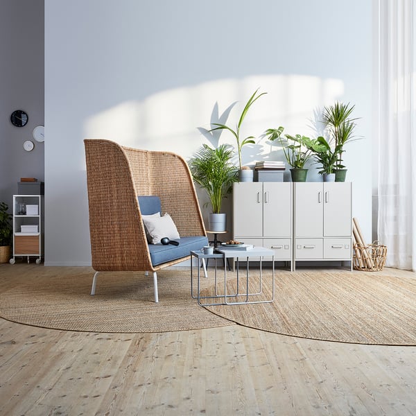 Modern living room with LOHALS natural jute rug, wicker chair, small table, white cabinets, and large window.