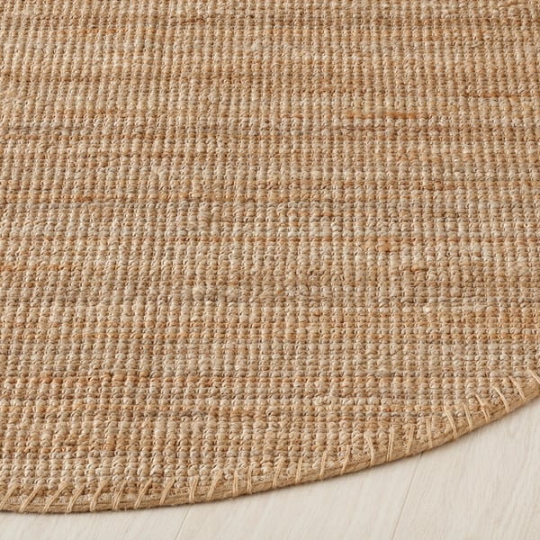 Natural jute rug displayed on wooden floor, showcasing its textured weave and earthy tones.
