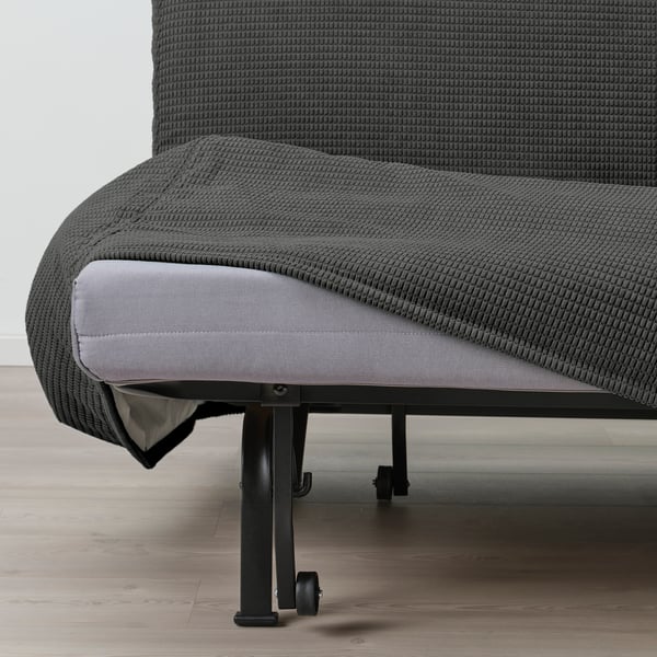 A grey sofa with a cushion pulled out, showing its convertible bed function. The sofa has a black metal frame with wheels.
