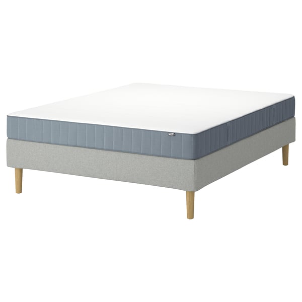 An IKEA LYNGÖR bed base and mattress in white and blue. The bed base has light grey fabric and wooden legs. The mattress has blue and white colours.