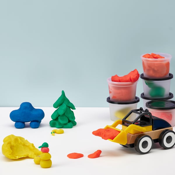 Coloured modelling dough in containers and a toy vehicle, demonstrating creative play and learning through sculpting.