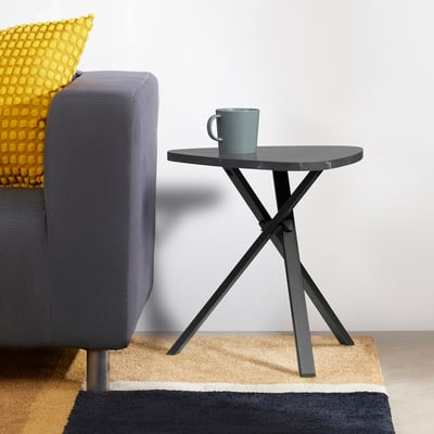 Modern grey side table with crisscrossed legs beside an armchair.