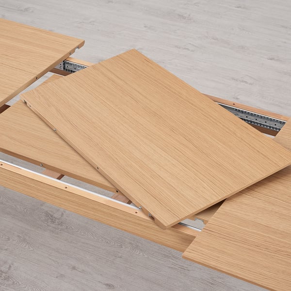 The underside of an extendable dining table with metal runners, illustrating the functional mechanism for adding extension leaves.