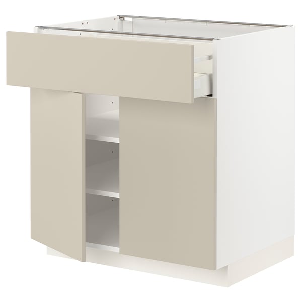 White METOD kitchen unit with beige drawer and shelves.