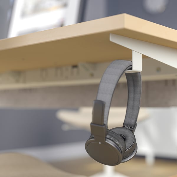 Headphones hang neatly from a hook on a height-adjustable desk for easy access and cable management.