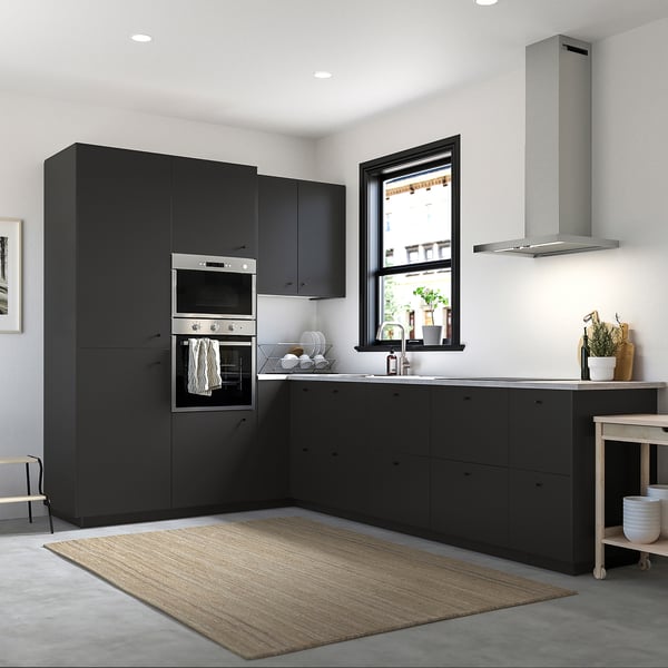 Modern kitchen with large black NICKEBO cabinets, sleek oven, and metallic range hood above sink; minimalist decor.
