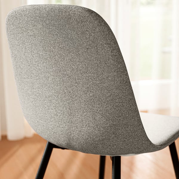 Close-up of a modern, upholstered chair with a grey, textured fabric and sleek metal legs.