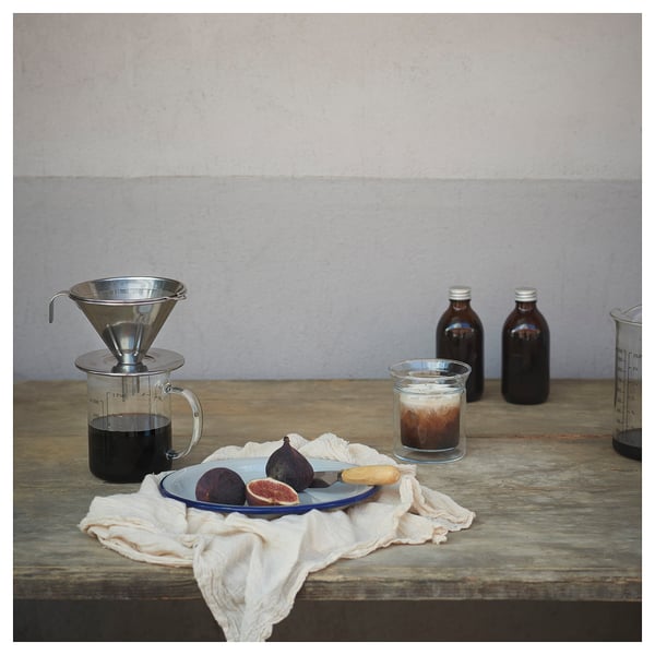 Silver metal coffee philtre on table with fruits and jars.