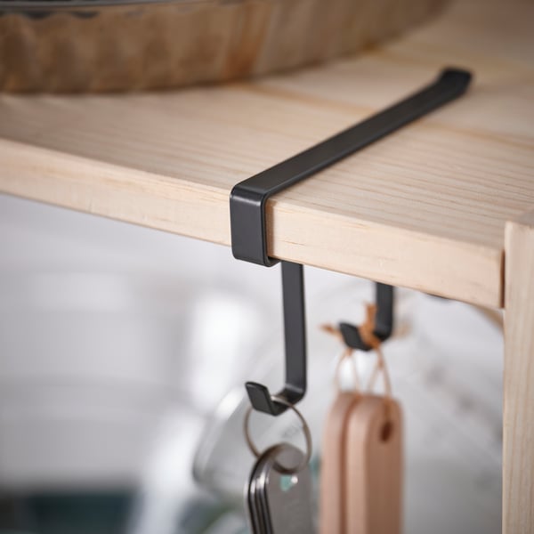 Wooden shelf with sturdy metal hooks holding items, showcasing quality craftsmanship.