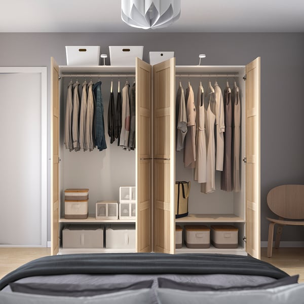 Open wooden wardrobe displaying clothes, boxes, and shelves. Clothes hang on rails, and storage boxes are on shelves below.