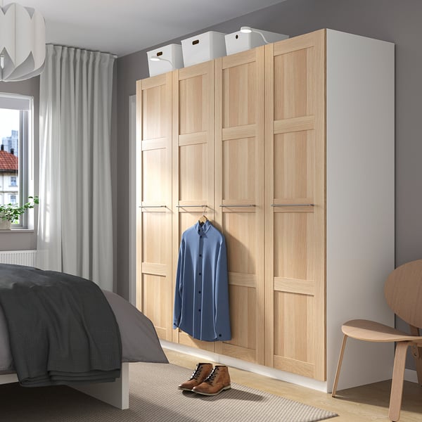 Modern light wood PAX wardrobe with blue shirt and storage boxes.