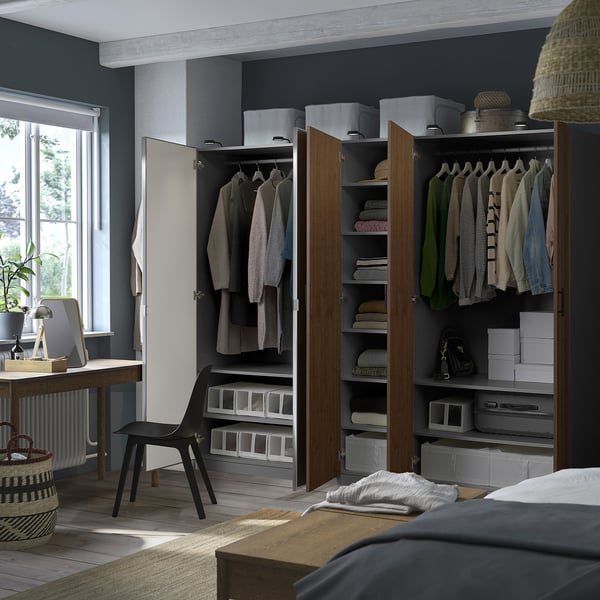 Bedroom with grey PAX wardrobes showing organised clothes, shelves, and boxes. One door open revealing hanging garments and folded items.