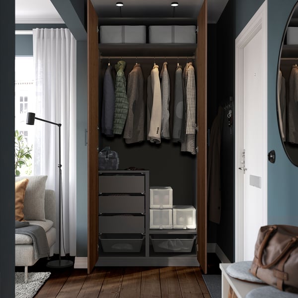 Open wardrobe with clothes hangers, drawers, boxes, and shelving showing organised storage space.