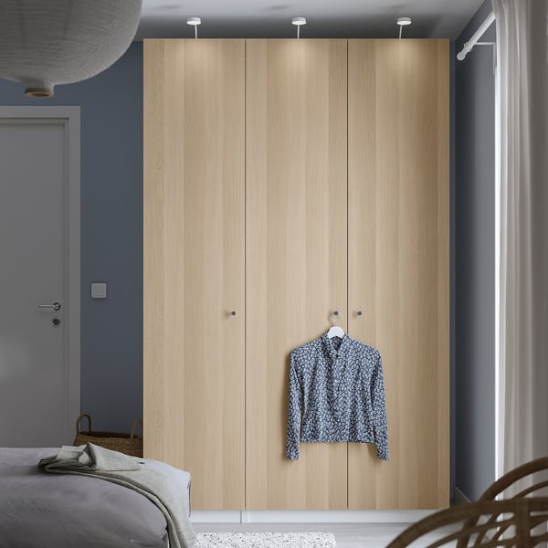 Minimalist bedroom with wooden PAX wardrobe, lighting, shirt, bed, basket.