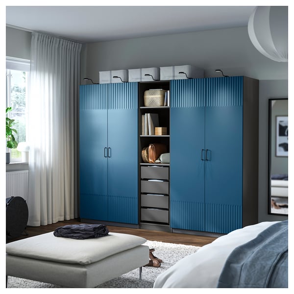 Blue ribbed wardrobe in bedroom, tall with multiple storage options.