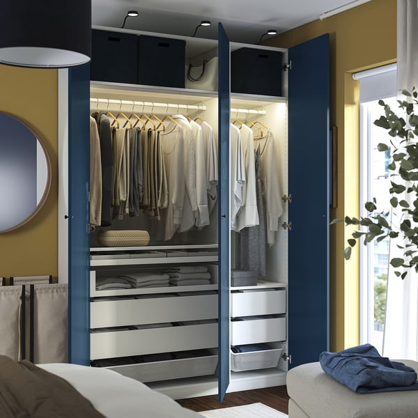 Open blue wardrobe showing organised clothes, drawers, and storage boxes with interior lighting.