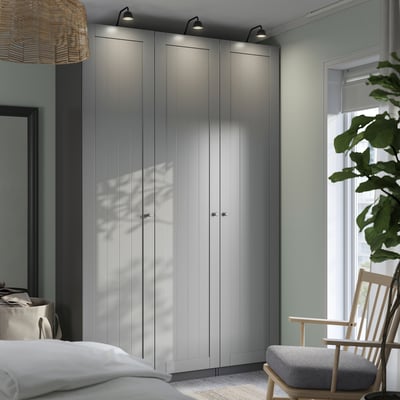 Modern bedroom with sleek ikea PAX wardrobes, lights, chair, and plant.