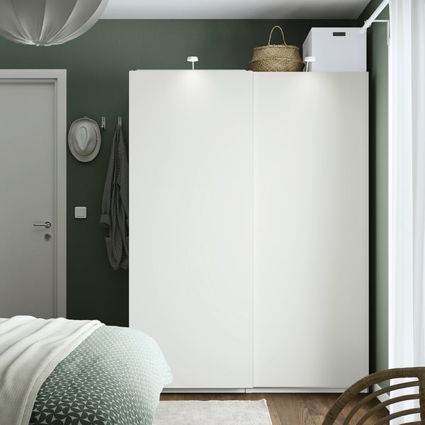 Modern bedroom with large white PAX wardrobe, green walls, grey bed, hanging hat, chair, and basket on top.