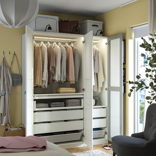White PAX wardrobe with mirrors, hangers, shelves, drawers, and internal lighting organises clothes neatly.