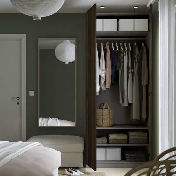 Modern bedroom with dark green walls and open wooden closet with clothes and lighting.