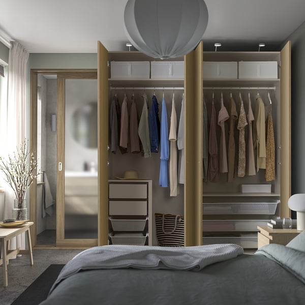 Modern bedroom with grey bed and open PAX wardrobe, showing organised storage.