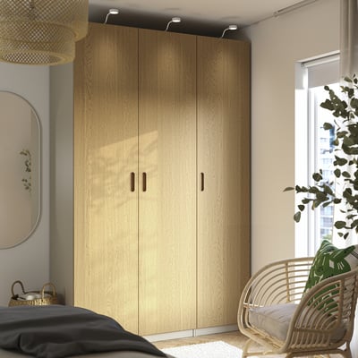 Light wood PAX wardrobe with two doors, tall, beside bed and window.