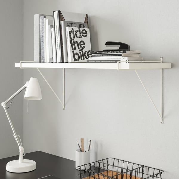 White PERSHULT shelf with books, lamp, pens. Modern, adjustable.