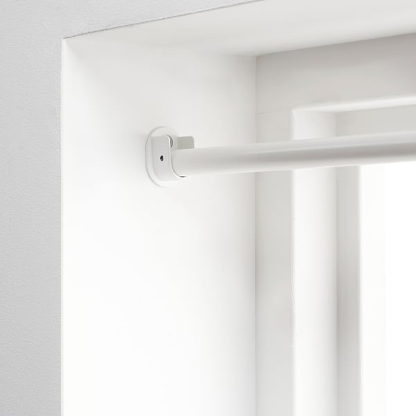 White adjustable curtain rod mounted on wall, part of IKEAs racka series, designed to extend across the entire wall for edge-to-edge privacy.