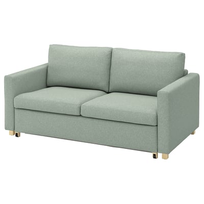 Light green SALTSJÖBADEN sofa-bed, minimalist design, cushioned, wooden legs.