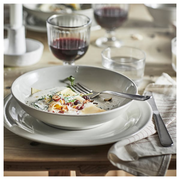 Rustic dinner set with sauce, wine, & folded napkin on wood table.