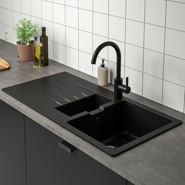 Modern kitchen sink with black tap and reversible drainboard.