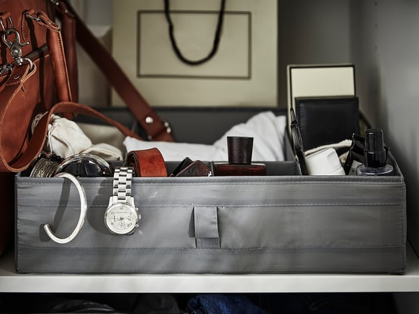 Grey SKUBB storage box for accessories and jewellery. Recycled polyester, with handles. White surface, leather bag.