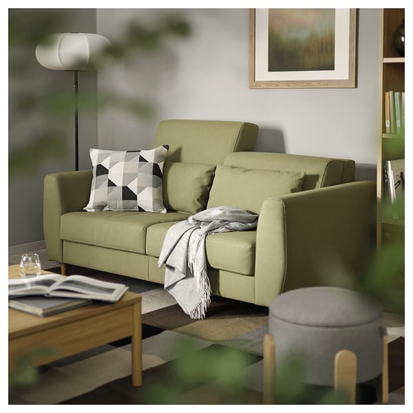 A modern living room with a green SLATORP sofa, soft cushions, books, and a cosy blanket.
