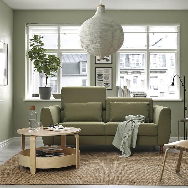 Modern green sofa in cosy living room with large window, coffee table, and pendant lamp.