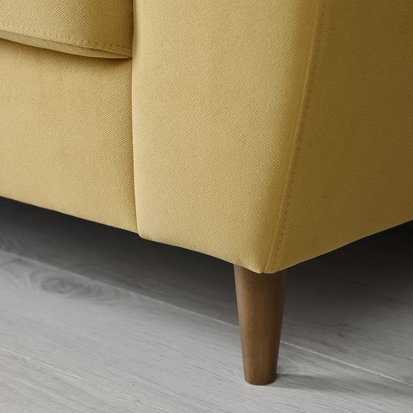 Yellow sofa close-up, showing sturdy wooden leg and plush fabric, emphasising comfort and modern design.