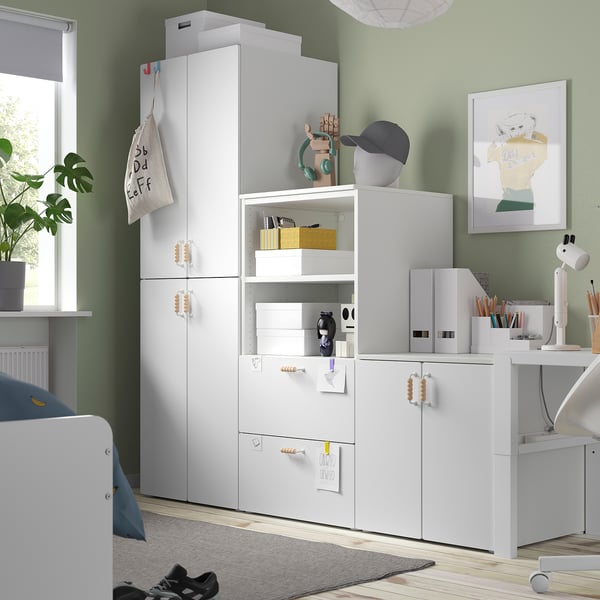 Modern white kids wardrobe with multiple compartments and items on top.