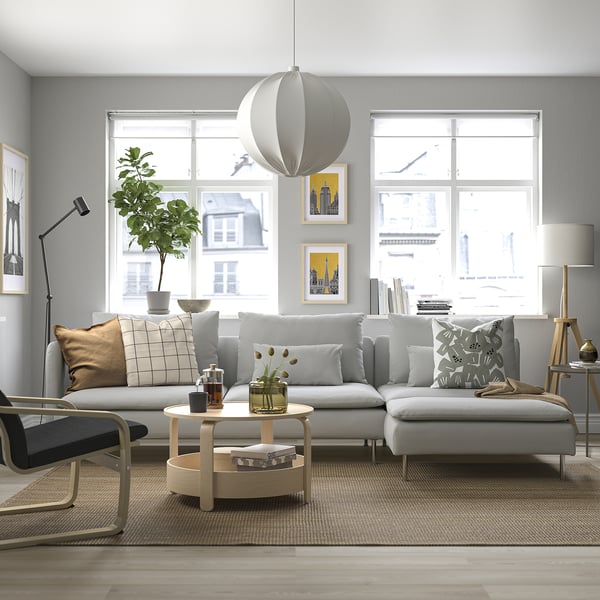 Grey SÖDERHAMN sofa set, deep-seated, with large cushions and round wooden table by a large window with city views.
