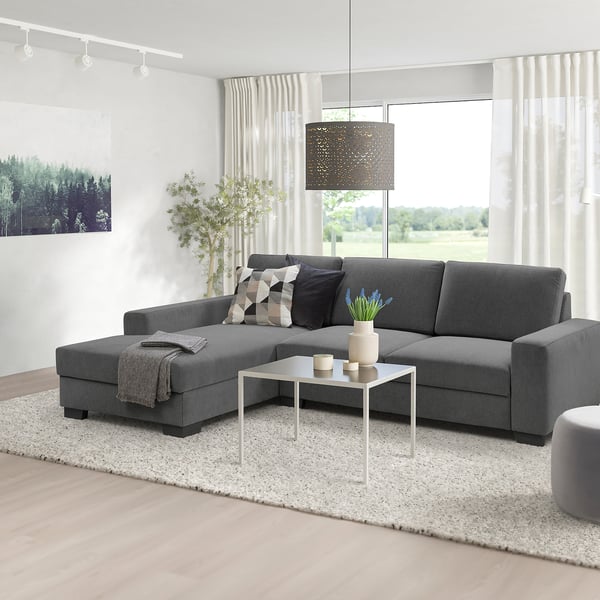 Modern minimalist living room with grey SÖRVALLEN l-shaped sofa, draped curtains, white coffee table, and pendant light.
