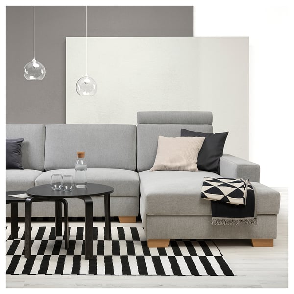 Modern living room with grey SÖRVALLEN sofa, black-white striped rug, black coffee table, hanging lamps, and accessories on sofa.