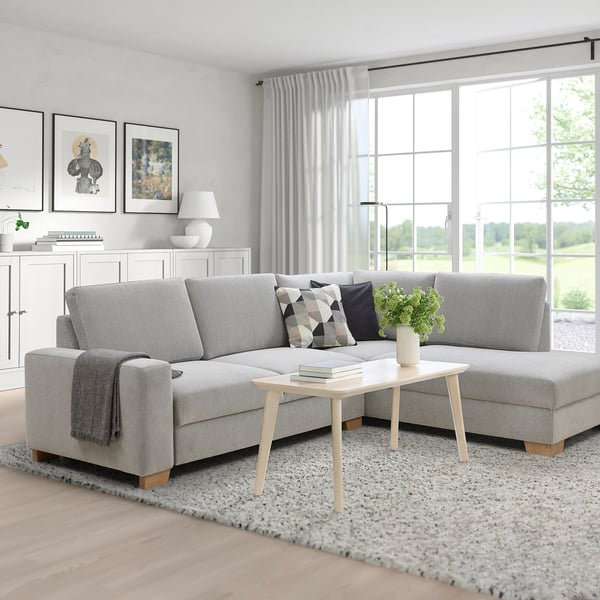 Modern living room with SÖRVALLEN grey sofa, large windows. Light wood coffee table, white curtains. Minimalist design.