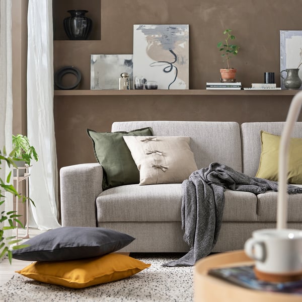 Modern living room with grey SÖRVALLEN sofa, colourful cushions, brown wall art.