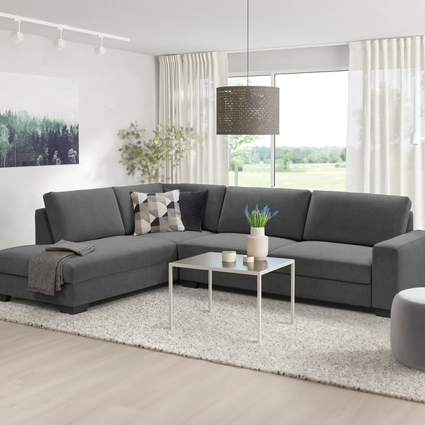 Modern living room with grey SÖRVALLEN sofa, white coffee table, blue flowers, pendant lamp, and large windows.