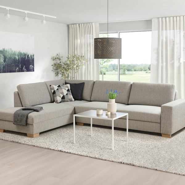 Minimalist living room with l-shape sofa, coffee table, large windows, nature view.