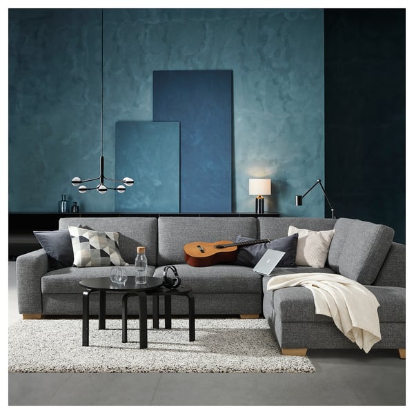 Modern grey sofa, SÖRVALLEN, with cushions, coffee table, guitar, laptop, and minimalist decor in a cosy living room.